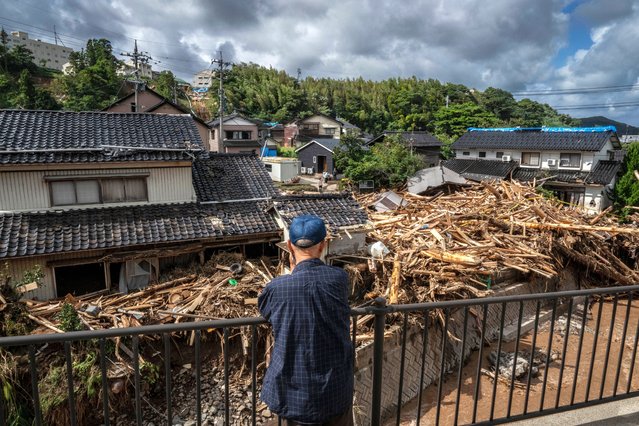 A man looks on as debris washed away from flooding is seen piled by houses along the Tsukada river following heavy rain in Wajima city, Ishikawa prefecture on September 23, 2024. Heavy rain that triggered floods and landslides on a Japanese penisula recovering from an earthquake this year killed at least six people, local media reported on September 23. (Photo by Yuichi Yamazaki/AFP Photo)