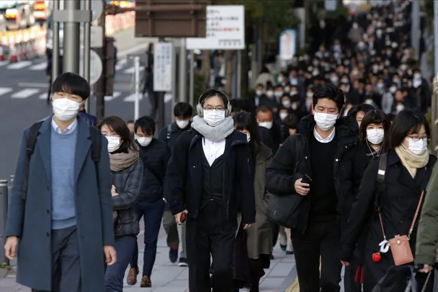 People wear masks as they commute during the morning rush hour Thursday, February 20, 2020, in Chuo district in Tokyo. A viral outbreak that began in China has infected more than 75,000 people globally. More than 1,000 cases have been confirmed outside mainland China. Most of the cases outside China involve people from a cruise ship quarantined at a Japanese port. (Photo by Kiichiro Sato/AP Photo)