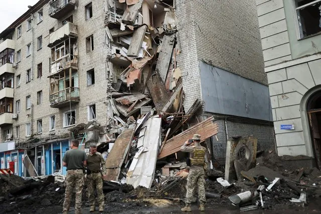 Ukrainian servicemen stand in front of Valentina Popovichuk's flat, where she was rescued after Russian shelling in a military strike, as Russia's invasion of Ukraine continues, in Kharkiv, Ukraine, July 11, 2022. (Photo by Nacho Doce/Reuters)