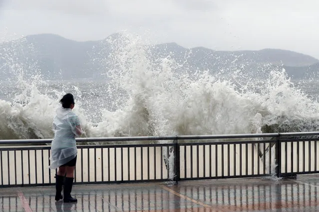 A woman stands beside a big wave on a waterfront Typhoon Hato hitting in Hong Kong, China on August 23, 2017. (Photo by Tyrone Siu/Reuters)