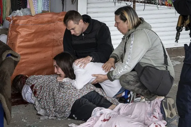 Sabina, center, cries next to her killed husband Artem Pogorelets after Russian shelling at Barabashovo market in Kharkiv, Ukraine, Thursday, July 21, 2022. (Photo by Evgeniy Maloletka/AP Photo)