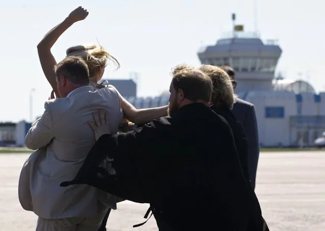 A topless protester from the Ukrainian feminist group Femen is blocked by a security guard and a priest as she tries to throw herself at the leader of the Russian Orthodox Church