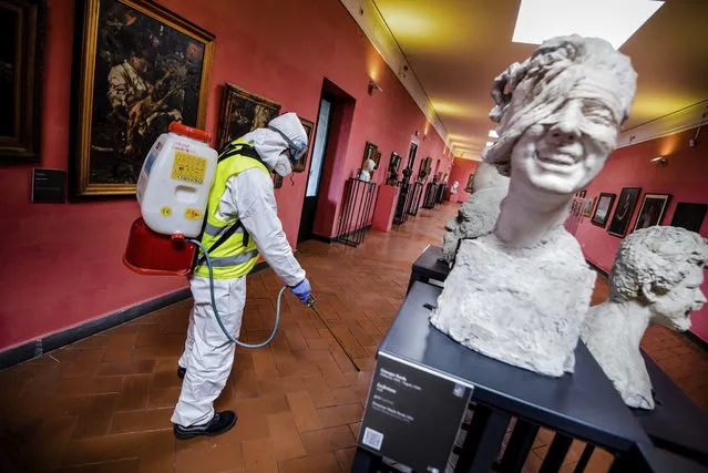 A worker sprays disinfectant as sanitization operations against Coronavirus are carried out in the museum hosted by the Maschio Angioino medieval castle, in Naples, Italy, Tuesday, March 10, 2020. (Photo by Alessandro Pone/LaPresse via AP Photo)