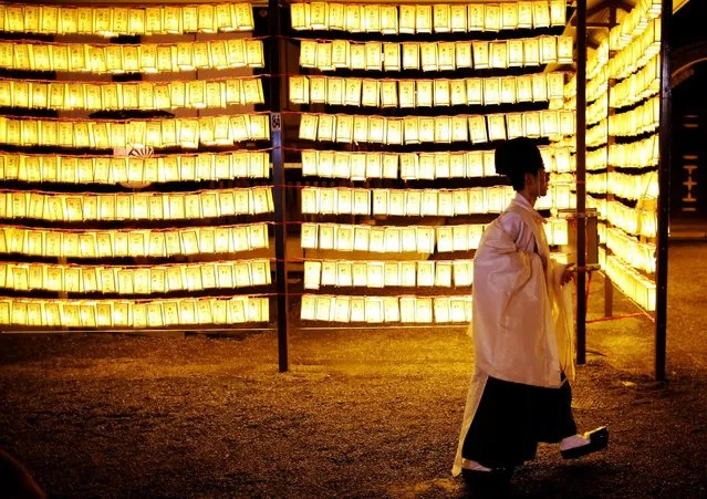A Shinto priest walks in front of thousands paper lanterns, which were displayed and lit up the precincts of the shrine, where more than 2.4 million war-dead are enshrined during the Mitama Festival at Yasukuni Shrine in Tokyo, Japan July 13, 2016. (Photo by Issei Kato/Reuters)