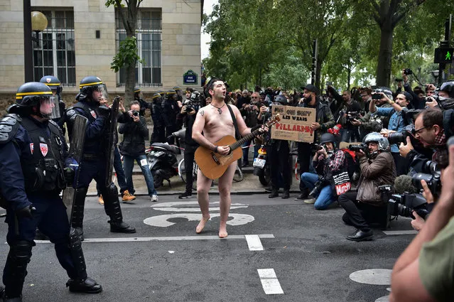 A naked man playing guitar stands in front of police officers during a protest called by several French unions against the labour law reform in Paris, on September 12, 2017. French unions launched a day of strikes and protests today against French President's flagship labour reforms, a key test as he stakes his presidency on overhauling the sluggish economy. More than 180 street protests are planned nationwide against the reforms, which are intended to tackle stubbornly high unemployment by loosening the rules that govern how businesses hire and fire people. (Photo by Christophe Archambault/AFP Photo)