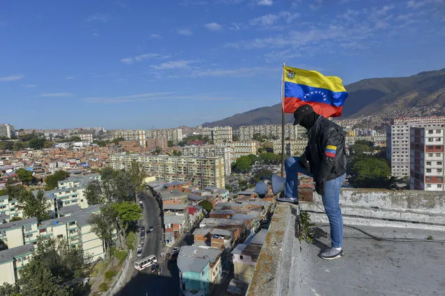 A member of a pro-government militia group stands on a roof overlooking the 23 de Enero neighborhood during an invasion drill in Caracas, Venezuela, Saturday, February 15, 2020. (Photo by Matias Delacroix/AP Photo)