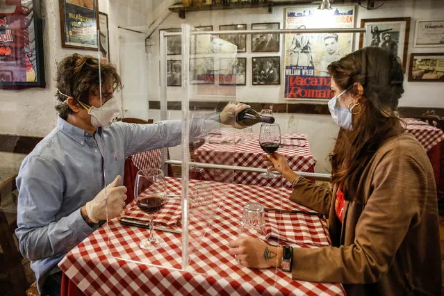 Valerio Calderoni, owner of an italian tipical restaurant, and his wife Martina, pose for a picture during a test for a of possible plexiglass separator between tables of restaurant “Il Ciak”, Trastevere district in Rome, Italy, 23 April 2020. Countries around the world are taking measures to stem the widespread of the SARS-CoV-2 coronavirus which causes the Covid-19 disease. (Photo by Fabio Frustaci/EPA/EFE)