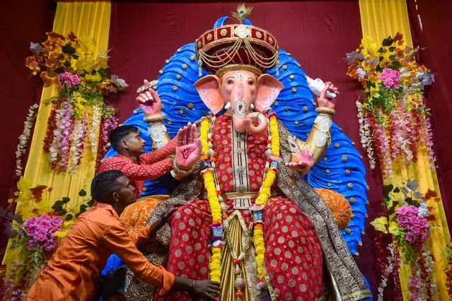 People are worshipping an idol of the Hindu god Ganesh, the deity of prosperity, inside a “pandal” a temporary makeshift tent on the first day of the ten-day-long Ganesh Chaturthi festival in Kolkata on August 31, 2022. (Photo by Sudipta Das/Pacific Press/Rex Features/Shutterstock)