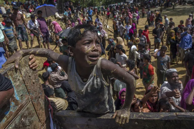 A Rohingya Muslim boy, who crossed over from Myanmar into Bangladesh, pleads with aid workers to give him a bag of rice near Balukhali refugee camp, Bangladesh, Thursday, September 21, 2017. With Rohingya refugees still flooding across the border from Myanmar, those packed into camps and makeshift settlements in Bangladesh are desperate for scant basic resources and fights erupt over food and water. (Photo by Dar Yasin/AP Photo)