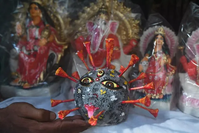A artisan displays a COVID-19 coronavirus model next to Hindu idols during a government-imposed nationwide lockdown as a preventive measure against the COVID-19 coronavirus, in Kolkata on April 23, 2020. (Photo by Dibyangshu Sarkar/AFP Photo)