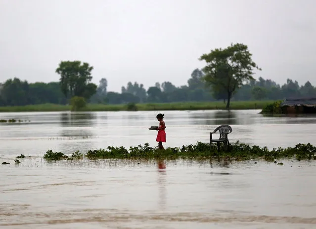 A girl carrying dishes walks along a flooded area in Janakpur, Nepal August 13, 2017. (Photo by Navesh Chitrakar/Reuters)