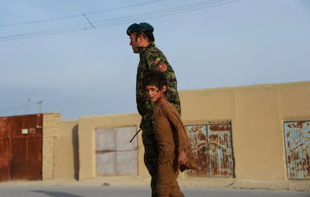 A wounded Afghan boy walks with an Afghan National Army (ANA) soldier at the site of a suicide attack in Dehdadi, a district close to the provincial capital Mazar-i-Sharif on February 8, 2016. A Taliban suicide bomber threw himself against a bus carrying Afghan army troops in northern Balkh province on February 8, killing three soldiers in the explosion, officials said. The incident comes as the militant group steps up attacks across the country in the fifteenth year of its insurgency against the Western-backed government in Kabul. (Photo by Farshad Usyan/AFP Photo)
