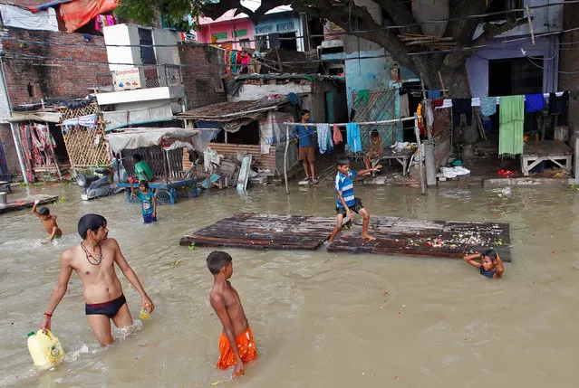 A boy walks on a partially submerged wooden bed outside a house in the flooded banks of the river Ganga after heavy rains in Allahabad, India, August 11, 2016. (Photo by Jitendra Prakash/Reuters)