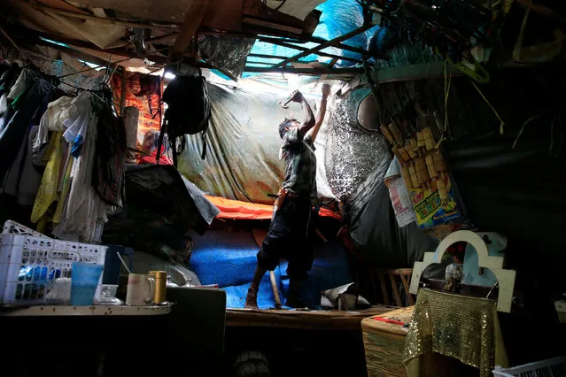 A resident fixes his damaged shanty after a tornado and torrential downpour brought on by monsoon rains battered a residential area in Baseco, Tondo city, metro Manila, Philippines August 15, 2016. (Photo by Romeo Ranoco/Reuters)