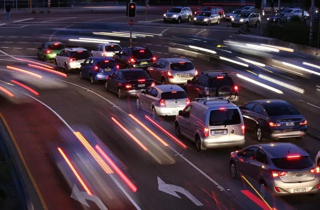 In this Wednesday, September 17, 2014, photo, the headlights and taillights of moving cars streak past stationary cars waiting for their turn at an intersection during the evening rush hour in Sydney. (Photo by Rick Rycroft/AP Photo)