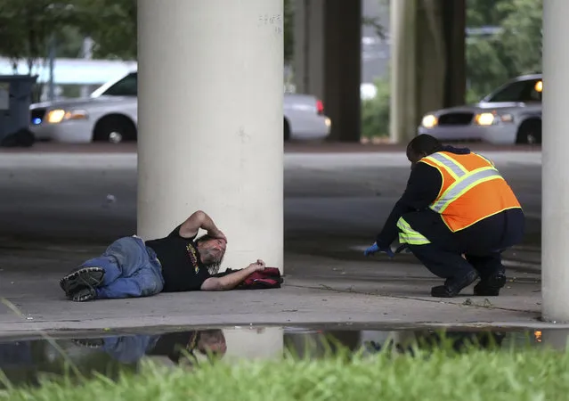 A sanitation employee, right, talks to a homeless person under the Pontchartrain Expressway, during a homeless sweep in New Orleans, in advance of approaching Hurricane Nate, Saturday, October 7, 2017. (Photo by Gerald Herbert/AP Photo)