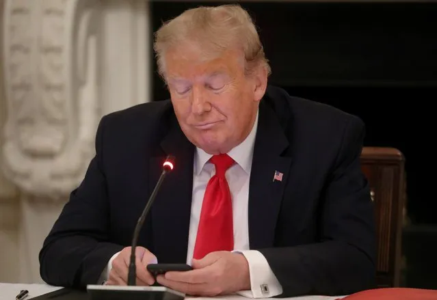 U.S. President Donald Trump is using a mobile phone during a roundtable discussion on the reopening of small businesses in the State Dining Room at the White House in Washington, U.S., June 18, 2020. (Photo by Leah Millis/Reuters)