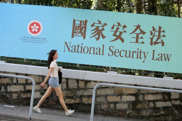 A woman walks past a promotional banner of the national security law for Hong Kong, in Hong Kong, Tuesday, June 30, 2020. China has approved a contentious law that would allow authorities to crack down on subversive and secessionist activity in Hong Kong, sparking fears that it would be used to curb opposition voices in the semi-autonomous territory. (Photo by Kin Cheung/AP Photo)