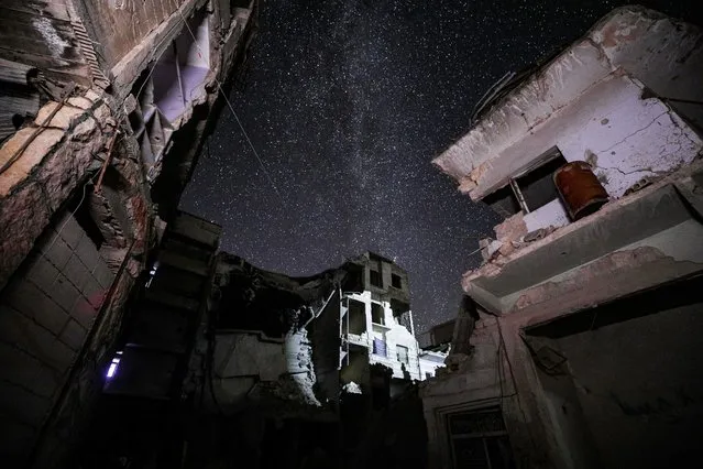 This long-exposure picture taken early on June 27, 2020 shows a view of buildings destroyed by prior bombardment in the town of Ariha in Syria's rebel-held northwestern Idlib province, as the Milky Way galaxy is seen in the night sky above. (Photo by Omar Haj Kadour/AFP Photo)