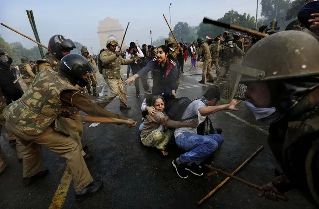 Protesters shield themselves as police beat them with sticks during a violent demonstration near the India Gate against a gang rape and brutal beating of a 23-year-old student on a bus last week, in New Delhi, India, December 23, 2012. The attack last Sunday has sparked days of protests across the country. (Photo by Kevin Frayer/Associated Press)