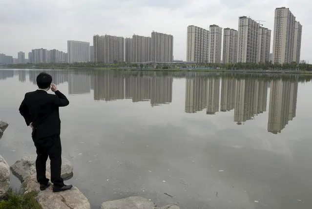 A man talks on his phone near a new residential compound in Taiyuan, Shanxi province, May 11, 2014. (Photo by Jon Woo/Reuters)