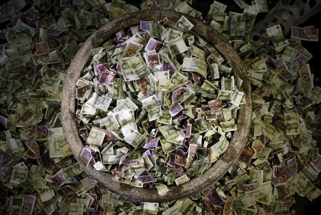 A jar overflowing with Chinese banknotes is pictured during the National Day holiday at Porcelain House in Tianjin, China, October 3, 2015. The banknotes were placed by visitors wishing for good fortune. Porcelain House, also known as China house, is a museum displaying pottery and antiques and its exterior and interior is decorated with hundreds of millions of ancient porcelain flakes, ancient bowls, dishes and vases. (Photo by Kim Kyung-Hoon/Reuters)
