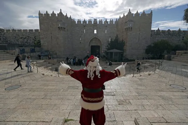 Issa Kassissieh dressed as Santa Claus greets people at the Damascus gate of the Old City of Jerusalem, 06 December 2022, as part of Christmas preparations. (Photo by Atef Safadi/EPA/EFE)