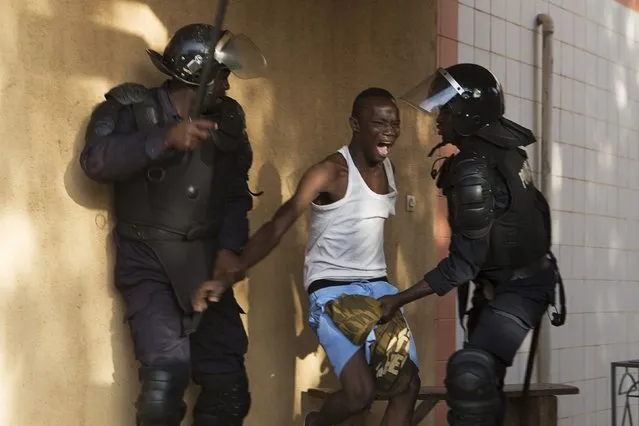 Riot police arrest an anti-government protester in Ouagadougou, capital of Burkina Faso, October 30, 2014. Thousands of protesters marched on Burkina Faso's presidential palace after burning the parliament building and ransacking state television offices on Thursday, forcing President Blaise Compaore to scrap a plan to extend his 27-year rule. (Photo by Joe Penney/Reuters)