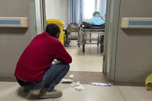 A man squats outside a treatment room as an elderly person receives help with breathing via a manual ventilator pump at the emergency department of the Baoding No. 2 Central Hospital in Zhuozhou city in northern China's Hebei province on Wednesday, December 21, 2022. (Photo by AP Photo/Stringer)