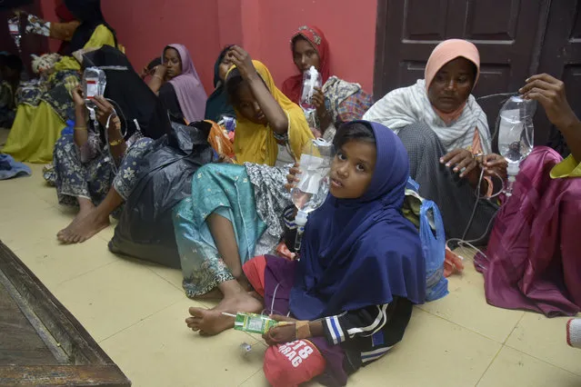 Ethnic Rohingya women and children sit on the floor upon arrival at a temporary shelter after their boat landed in Pidie, Aceh province, Indonesia, Monday, December 26, 2022. A second group in two days of weak and exhausted Rohingya Muslims landed on a beach in Indonesia's northernmost province of Aceh on Monday after weeks at sea, officials said. (Photo by Rahmat Mirza/AP Photo)