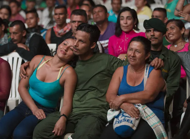 Willington, center, a rebel of the Revolutionary Armed Forces of Colombia, FARC, sits with his mother Judith, right, and girlfriend during a concert in the group's 10th conference , in Yari Plains, southern Colombia, Sunday, September 18, 2016. FARC leaders and delegates are gathering to debate and vote on the accord reached last month with the Colombian government to end five decades of war. (Photo by Ricardo Mazalan/AP Photo)