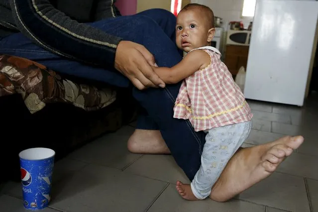 Jeison Rodriguez, 19, the living person with the largest feet in the world, holds his niece Osmariel with the help of his foot at his house in Maracay, Venezuela, October 14, 2015. (Photo by Carlos Garcia Rawlins/Reuters)