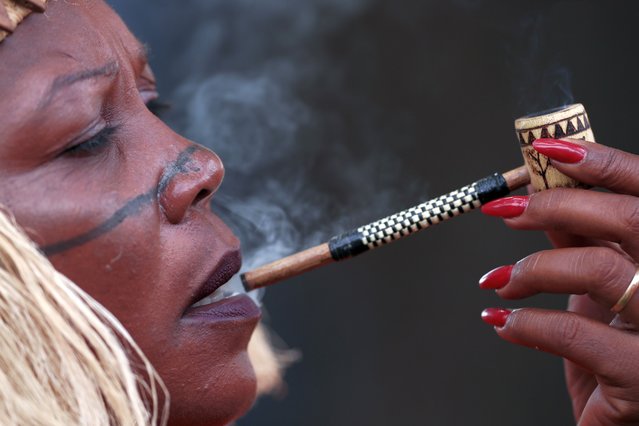An Indigenous woman smokes a pipe during the 20th annual Free Land Indigenous Camp in Brasilia, Brazil, Tuesday, April 23, 2024. The 7-day event aims to show the unity of Brazil's Indigenous peoples in their fight for the demarcation of their lands and their rights. (Photo by Luis Nova/AP Photo)
