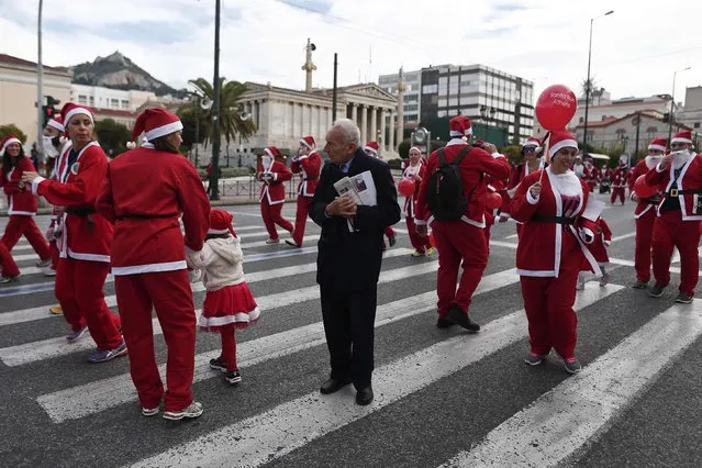 A man stands among people dressed in Santa costumes taking part in the Santa Claus Run in Athens December 7, 2014. (Photo by Alkis Konstantinidis/Reuters)