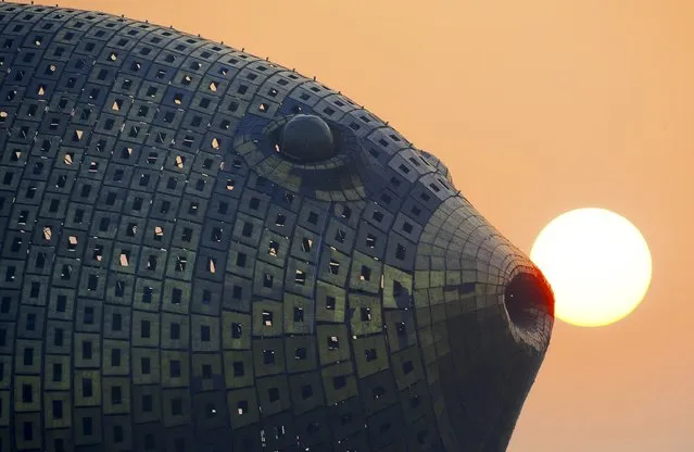 The sun sets behind a viewing tower in the shape of a giant puffer fish, on the banks of a river in Yangzhong county, Jiangsu province, China, October 23, 2015. Encased in 8,920 copper plates and built at a cost of around 70 million yuan ($11.4 million), the tower on an island in Yangzhong county, eastern Jiangsu province, hovers 15 storeys above ground. (Photo by Reuters/Stringer)