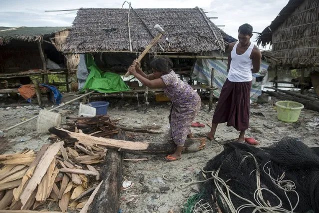 A woman chops firewood as her husband watches from behind her in Kyaukpyu township, Rakhine state, Myanmar October 6, 2015. (Photo by Soe Zeya Tun/Reuters)