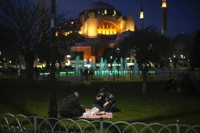 People break their fast after dusk on the first day of Ramadan backdropped by the iconic Byzantine-era Hagia Sophia mosque in Istanbul, Turkey, Thursday, March 23, 2023. Abstaining from all food and drink – not even a sip of water is allowed – and sеxual intercourse from dawn to sunset during the Muslim holy month of Ramadan is regarded as an act of piety and devotion to God and an exercise in self-restraint. (Photo by Francisco Seco/AP Photo)