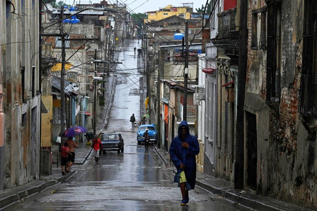 People walk along a street in the rain ahead of Hurricane Melissa's landfall, in Santiago de Cuba, Cuba, on October 28, 2025. (Photo by Norlys Perez/Reuters)