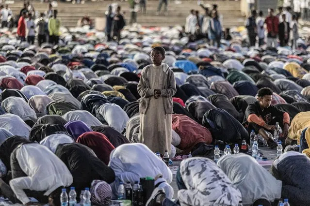 A boy stands as Muslim devotees pray at sunset prior to an open Iftar, fast-breaking dinner, held during the holy Islamic month of Ramadan in Meskel Square in Addis Ababa on April 8, 2023. (Photo by Amanuel Sileshi/AFP Photo)