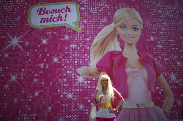 Model Ina Blaubeer poses with a Barbie doll in front a “Barbie Dreamhouse” of Mattel's Barbie dolls in Berlin, May 16, 2013. (Photo by Fabrizio Bensch/Reuters)