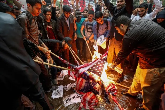 Iranians pour fuel on US flags set aflame during an anti-US demonstration outside the former US embassy headquarters in the capital Tehran on May 9, 2018. Iranians reacted with a mix of sadness, resignation and defiance on May 9 to US President Donald Trump's withdrawal from the nuclear deal, with sharp divisions among officials on how best to respond.
For many, Trump's decision on Tuesday to pull out of the landmark nuclear deal marked the final death knell for the hope created when it was signed in 2015 that Iran might finally escape decades of isolation and US hostility. (Photo by Atta Kenare/AFP Photo)