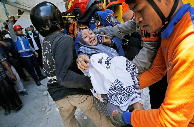 Members of the search and rescue operations carry a relative of the victim of a collapsed building, after a hall collapsed while students were praying at the Al-Khoziny Islamic boarding school on Monday, in Sidoarjo, East Java province, Indonesia, on October 1, 2025. (Photo by Dipta Wahyu/Reuters)