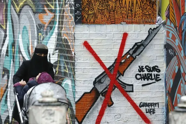 A woman pushes a pram past a “Je Suis Charlie” street art near Brick Lane in east London January 14, 2015. (Photo by Luke MacGregor/Reuters)