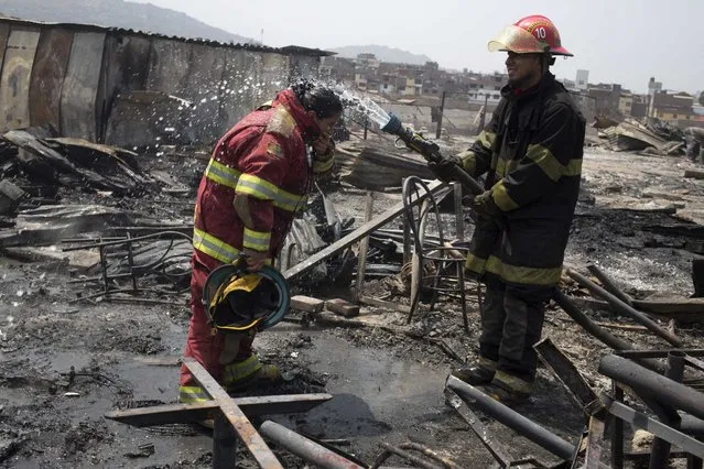 Firefighters cool off amid charred debris following an early morning fire that destroyed hundreds of homes, in the shantytown known as Cantagallo, in Lima, Peru, Friday, November 4, 2016. (Photo by Martin Mejia/AP Photo)