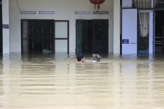 In this Sunday, June 24, 2018, photo, a man swims with his dog in the floodwaters in northern province of Ha Giang, Vietnam. Flash floods and landslides triggered by heavy rains hit northern Vietnam. (Photo by Minh Tam/Vietnam News Agency via AP Photo)