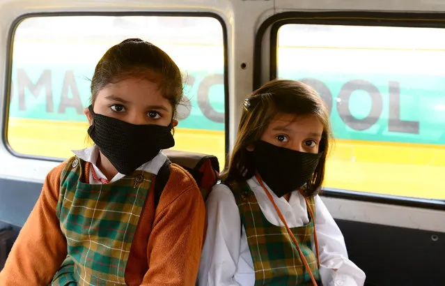 Indian school children wear masks as they sit inside a school cab as schools re- open after three days of closure due to smog, in New Delhi on November 10, 2016. (Photo by Sajjad Hussain/AFP Photo)