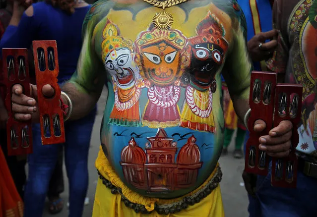 A Hindu devotee with his body painted with the images of Hindu god Jagannath, his brother Balabhadra and sister Subhadra, sings hymns during the annual Rath Yatra, or chariot procession, in Ahmedabad, India July 14, 2018. (Photo by Amit Dave/Reuters)