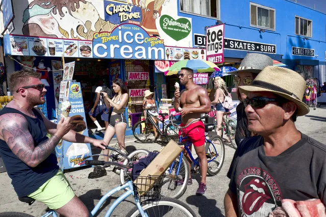 Tourists eat ice cream to cool off along the Venice Beach strand in Los Angeles, Tuesday, July 24, 2108. Scorching heat radiated across the U.S. Southwest on Tuesday, with the highest temperatures expected in California's Death Valley during a week that forecasters say could prove to be the region's hottest this year. (Photo by Richard Vogel/AP Photo)