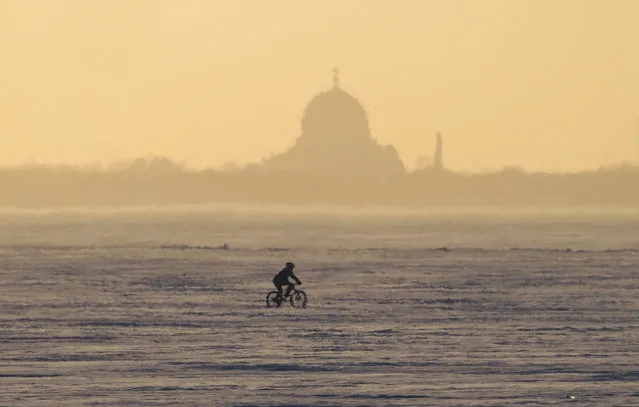 A man rides a bike in the frozen Finnish Gulf outside St. Petersburg, Russia, Wednesday, March 10, 2021. (Photo by Dmitri Lovetsky/AP Photo)