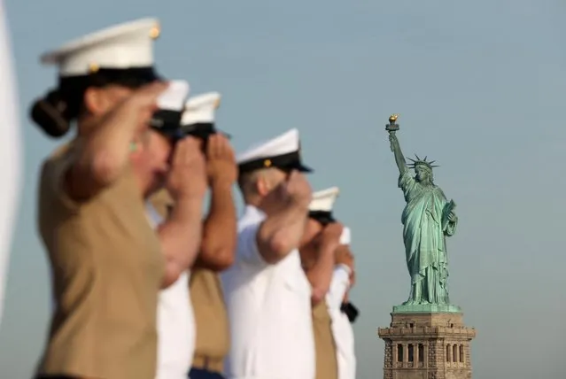 Members of the U.S. Marines and the U.S. Navy salute as they stand on the flight deck of the USS Bataan, a U.S. Navy Wasp-class amphibious assault ship, as it passes by the Statue of Liberty among a parade of ships during Fleet Week 2022 in New York, U.S. May 25, 2022. (Photo by Andrew Kelly/Reuters)